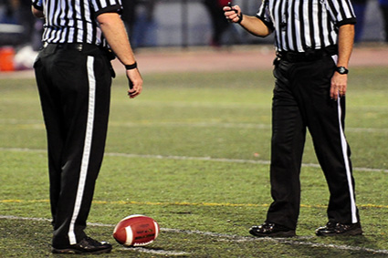 Two football officials are standing on the field.