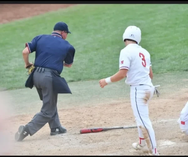 A baseball player is running to the plate